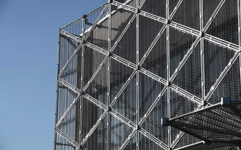 Struttura geometrica di un edificio moderno con pannelli a rete metallica, esempio di materiali da costruzione innovativi.