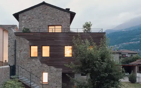 Facciate case di campagna esterni con pietra e legno, un connubio tra antico e moderno. Scale esterne conducono a un tetto-terrazza.