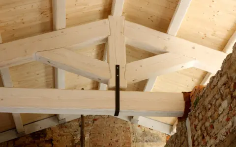 Struttura di una capriata in legno, con travi a vista e tavolato in abete. La robustezza della capriata in legno è evidente.