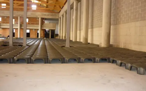 Struttura in costruzione con file di elementi prefabbricati che creano un vuoto sanitario. Colonne e pareti in mattoni visibili.