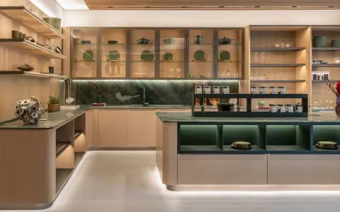Una cucina moderna con un'isola centrale. Il piano di lavoro e il paraschizzi in marmo verde creano un contrasto elegante con le ante in legno chiaro. Il colore verde domina, donando un tocco di natura e raffinatezza.