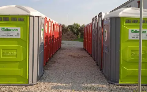 File di bagni chimici portatili, verdi e rossi, pronti per essere installati. Servizi igienici normativa rispettata.