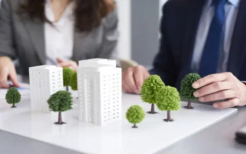 Modelli di edifici e alberi su un tavolo, che illustrano il **social housing significato** e la pianificazione urbana sostenibile.