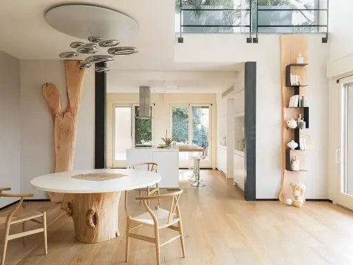 Interni case in legno moderne con tavolo scultoreo e cucina a vista.