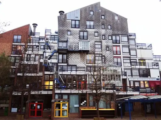 Edificio residenziale con facciata a mosaico, balconi e scale esterne, un esempio di architettura di Lucien Kroll.