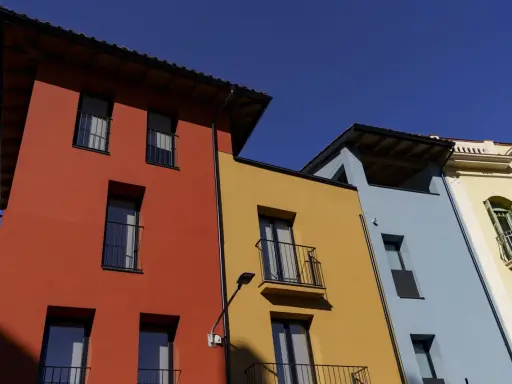 Edifici colorati con facciata giallo ocra, rosso e azzurro sotto un cielo limpido.