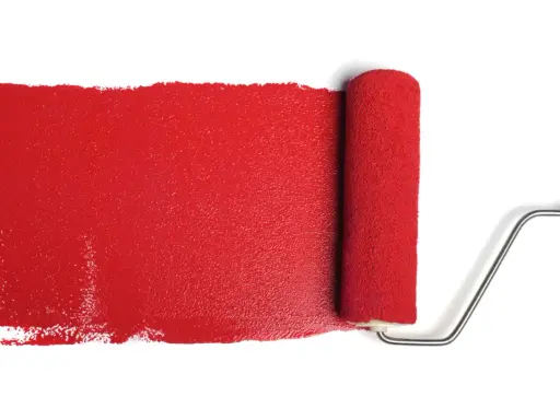 Rullo da pittura stende una striscia di vernice rosso antico, ideale per il colore esterno di una casa.