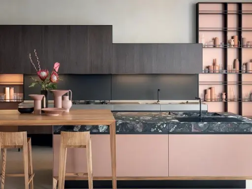 Cucine moderne con un mix di colori audaci: ante rosa cipria, top in marmo scuro e scaffalature color rame.