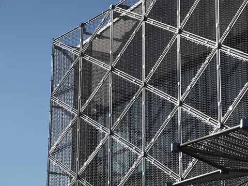 Struttura geometrica di un edificio moderno con pannelli a rete metallica, esempio di materiali da costruzione innovativi.