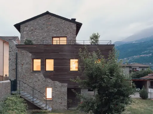 Facciate case di campagna esterni con pietra e legno, un connubio tra antico e moderno. Scale esterne conducono a un tetto-terrazza.