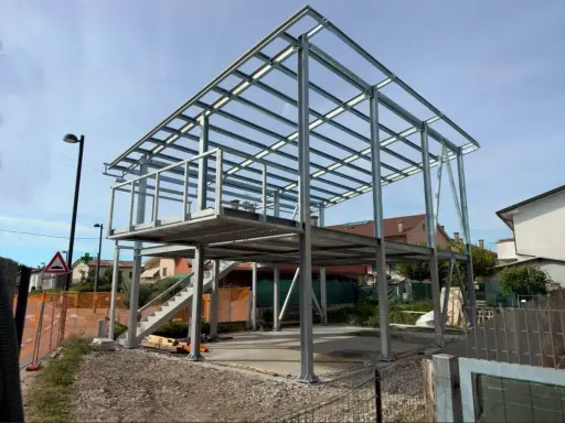 Struttura in acciaio per una casa in costruzione, con impalcati e tettoia visibili. Nessun difetto casa in acciaio evidente in questa fase.