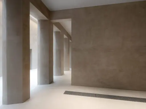 Colonnato moderno con pareti e pilastri in intonaco o stucco color sabbia, illuminato da luce soffusa.
