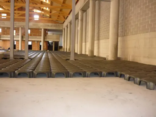 Struttura in costruzione con file di elementi prefabbricati che creano un vuoto sanitario. Colonne e pareti in mattoni visibili.