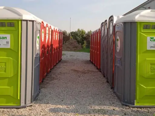 File di bagni chimici portatili, verdi e rossi, pronti per essere installati. Servizi igienici normativa rispettata.