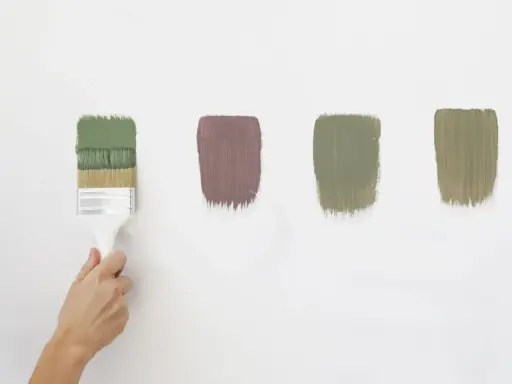 Pennello con vernici ecologiche in diverse tonalità di verde e un tocco di malva su sfondo bianco.