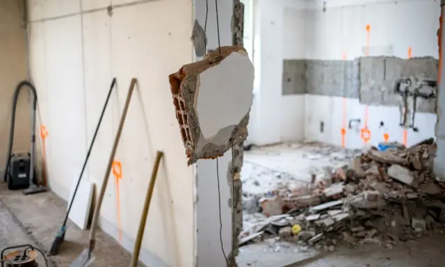 Demolizione di un muro interno, con detriti e attrezzi da lavoro. L'abbattimento muro interno senza CILA è un'operazione delicata.