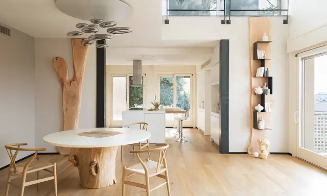Interni case in legno moderne con tavolo scultoreo e cucina a vista.