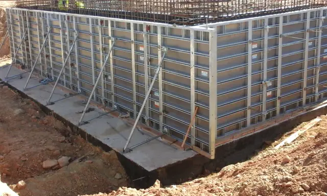 Casse edili metalliche montate per gettare una fondazione in cemento armato, con armature metalliche visibili in alto.