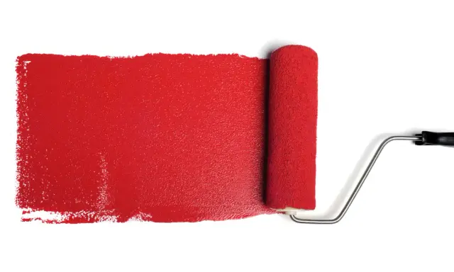 Rullo da pittura stende una striscia di vernice rosso antico, ideale per il colore esterno di una casa.