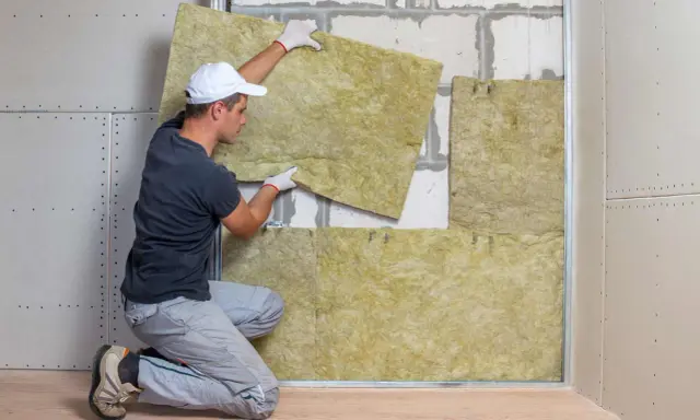 Operaio posiziona pannelli per isolamento termico soffitto dall'interno. Lavori di ristrutturazione in corso.