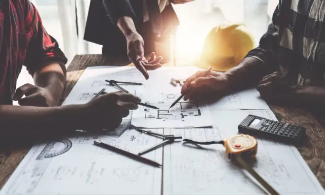 Architetti discutono progetti, cercando soluzioni per sanare un abuso edilizio commesso dal precedente proprietario.