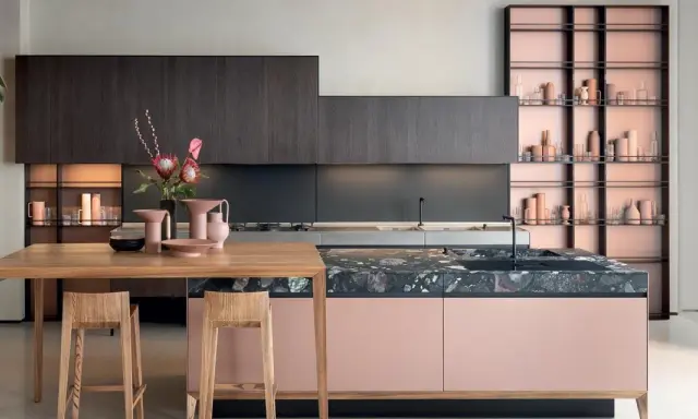 Cucine moderne con un mix di colori audaci: ante rosa cipria, top in marmo scuro e scaffalature color rame.