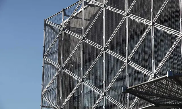 Struttura geometrica di un edificio moderno con pannelli a rete metallica, esempio di materiali da costruzione innovativi.