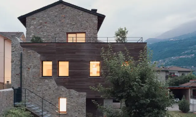Facciate case di campagna esterni con pietra e legno, un connubio tra antico e moderno. Scale esterne conducono a un tetto-terrazza.