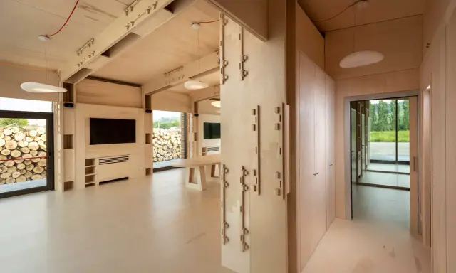 Interno di moderni edifici in legno con travi a vista, pareti in compensato e un'area living con TV.