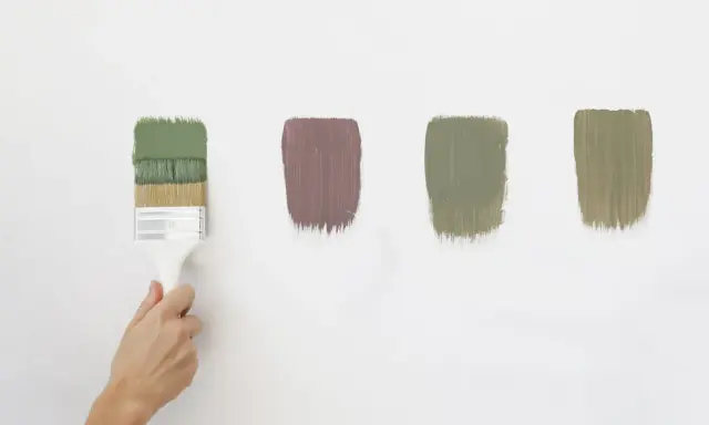 Pennello con vernici ecologiche in diverse tonalità di verde e un tocco di malva su sfondo bianco.