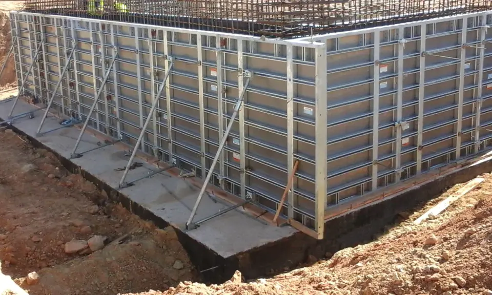Casse edili metalliche montate per gettare una fondazione in cemento armato, con armature metalliche visibili in alto.