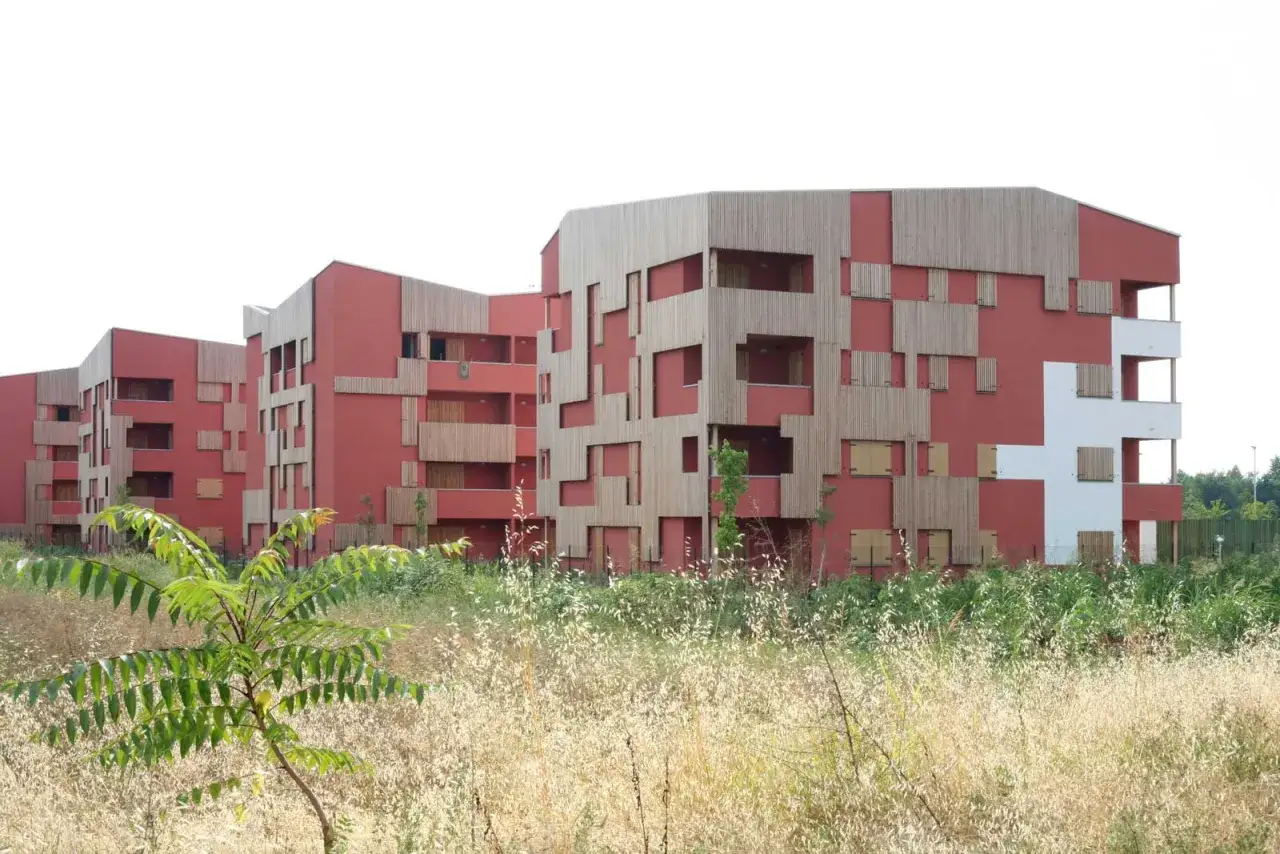Edifici moderni con facciate rosse e pannelli in legno, un esempio di social housing significato.