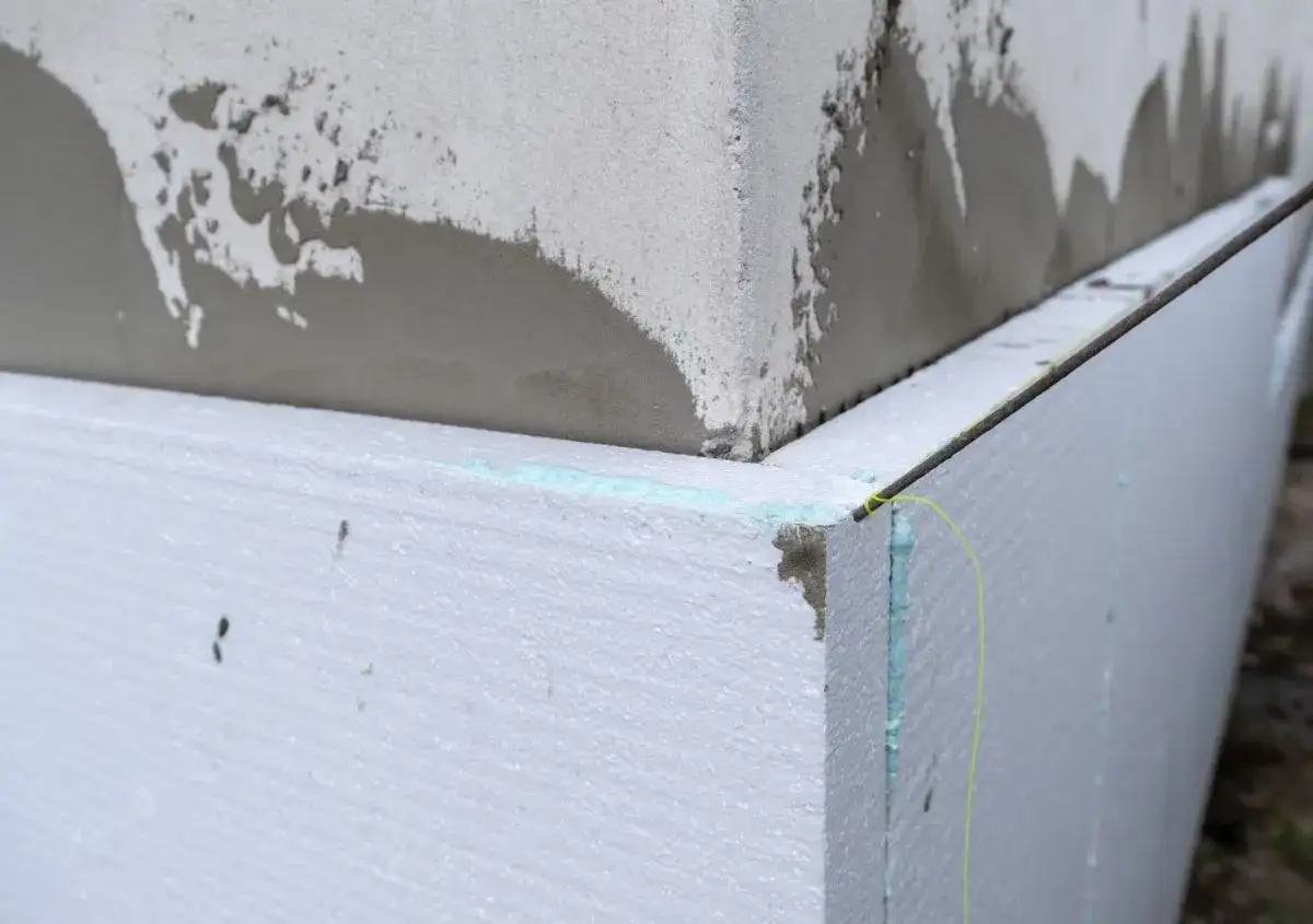 Angolo di un edificio con cappotto termico in polistirene. Si nota la malta applicata e una leggera condensa interstiziale tra i materiali.