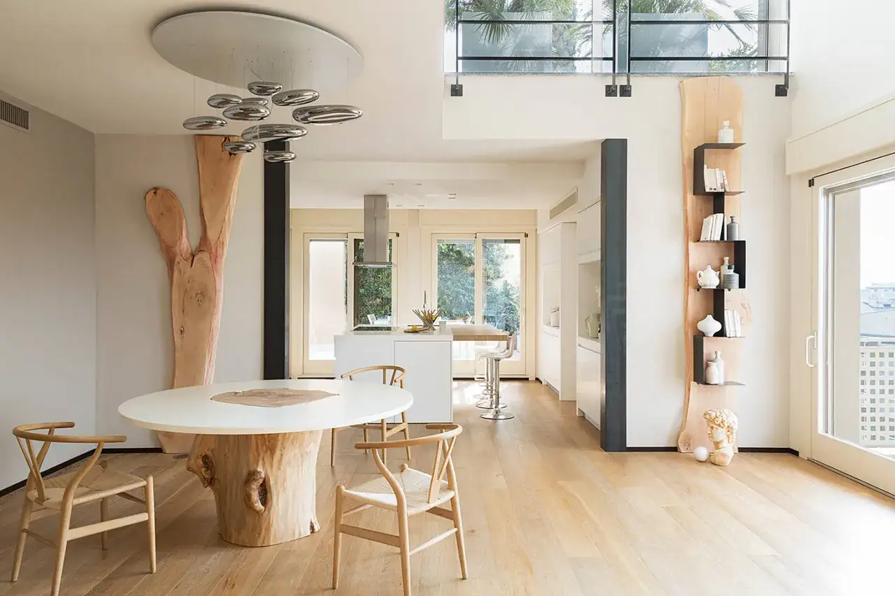 Interni case in legno moderne: tavolo con base in tronco, sedie in legno, cucina a vista e scaffali decorativi.