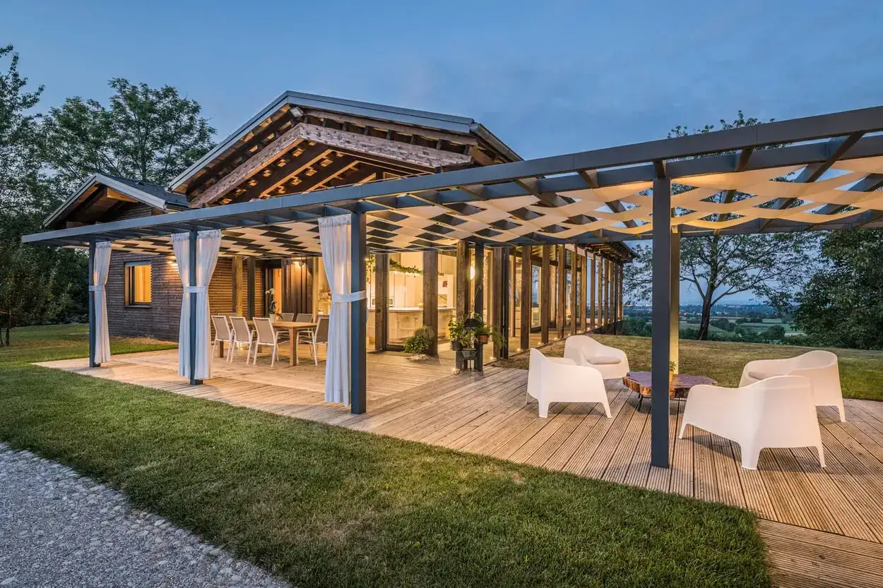 Moderna casa prefabbricata con ampio portico in legno, arredi esterni e vista panoramica. Soluzioni abitative innovative, anche senza concessione edilizia.