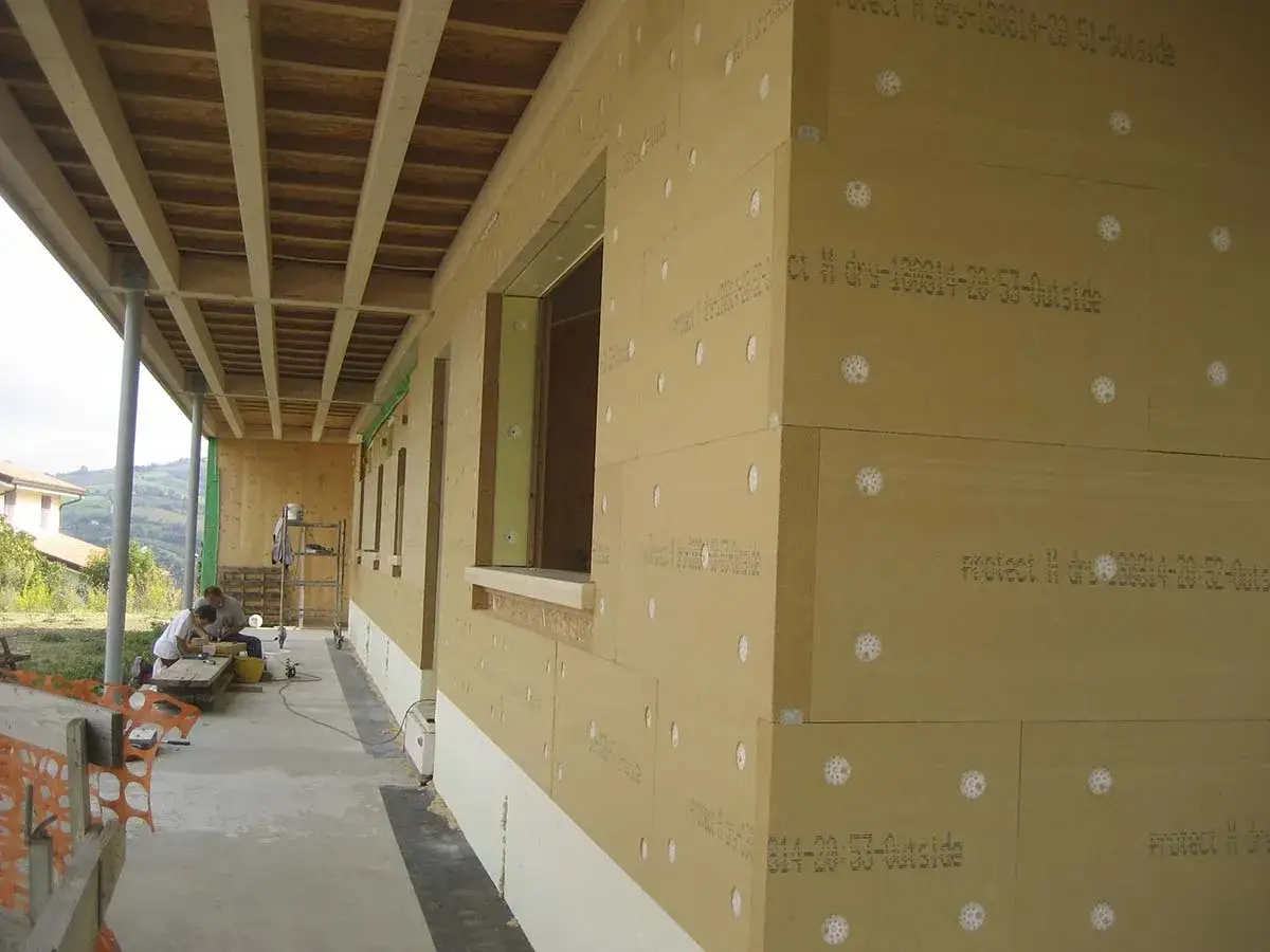 Pannelli in fibra di legno per cappotto interno, con fori visibili, in fase di installazione su un edificio in costruzione.