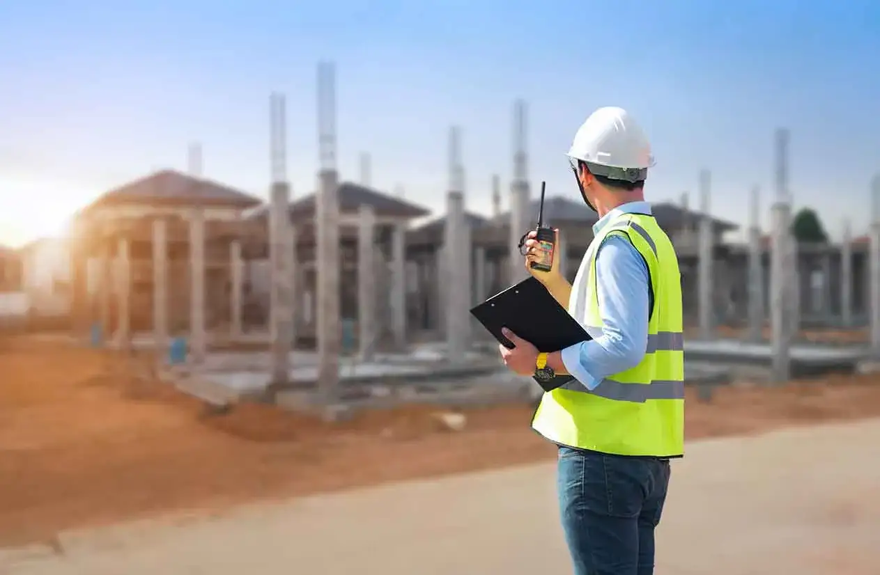 Un responsabile di cantiere mansioni supervisiona la costruzione di case, con walkie-talkie e appunti.