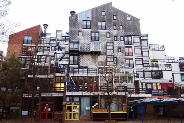 Edificio residenziale con facciata a mosaico, balconi e scale esterne, un esempio di architettura di Lucien Kroll.