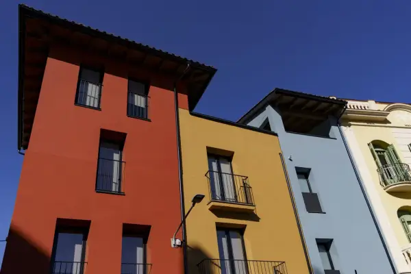 Edifici colorati con facciata giallo ocra, rosso e azzurro sotto un cielo limpido.